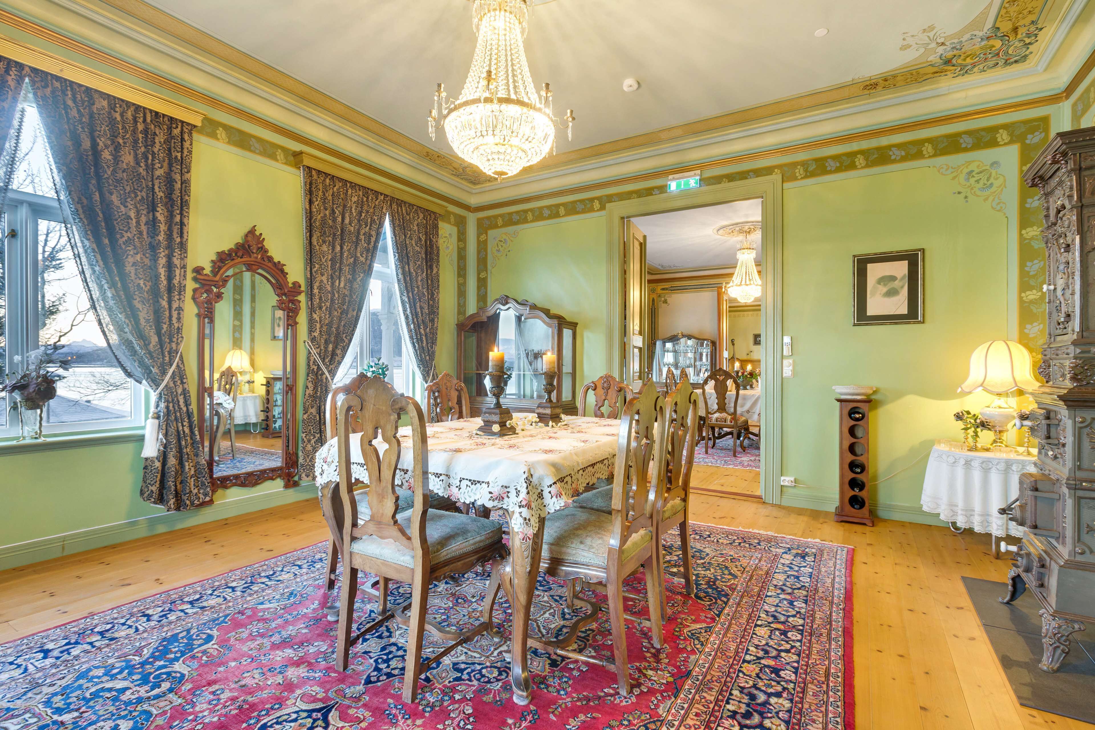 A room with a chandelier, ornate furniture, and a large mirror.