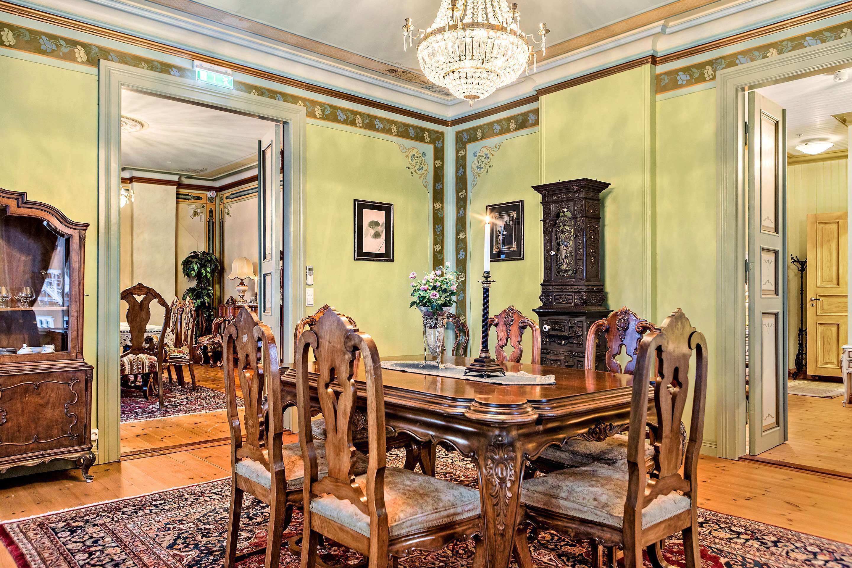 A formal dining room with a large wooden table, ornate chairs, and a chandelier.