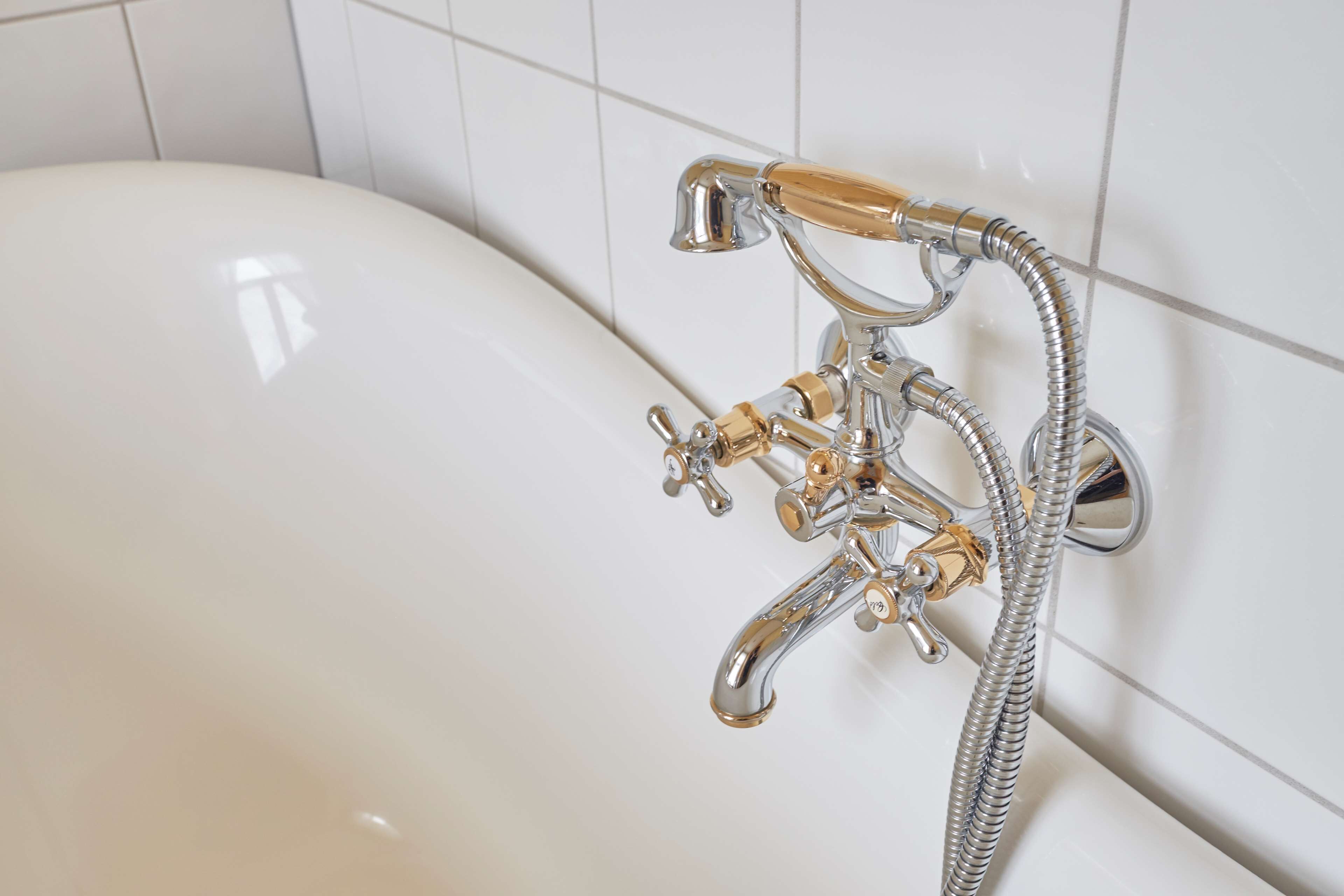 Una bañera con grifo y ducha de cromo.