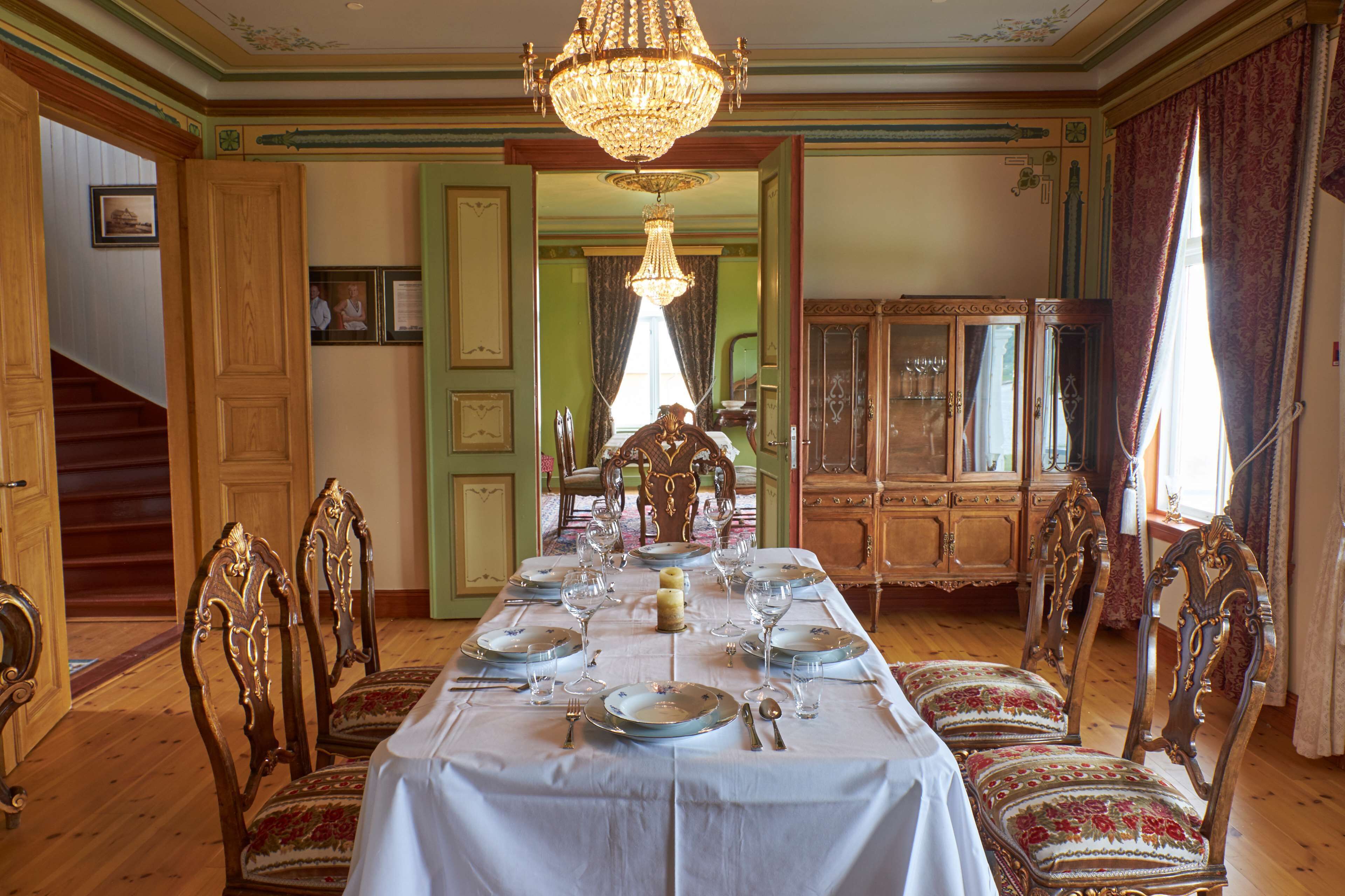 Comedor con una larga mesa dispuesta para una comida, rodeada de sillas decorativas.