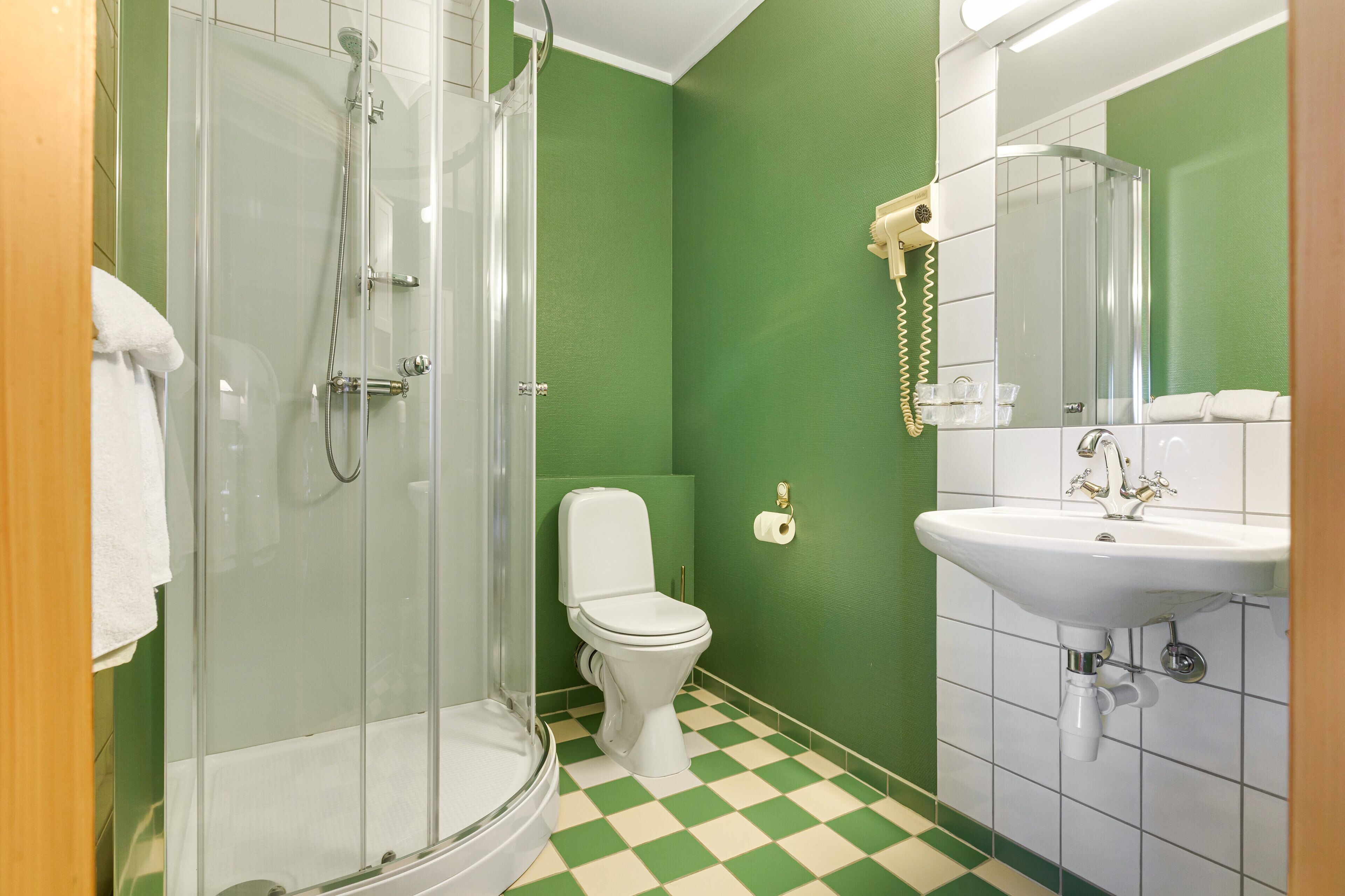 A bathroom with a glass-enclosed shower, a toilet, and a sink.