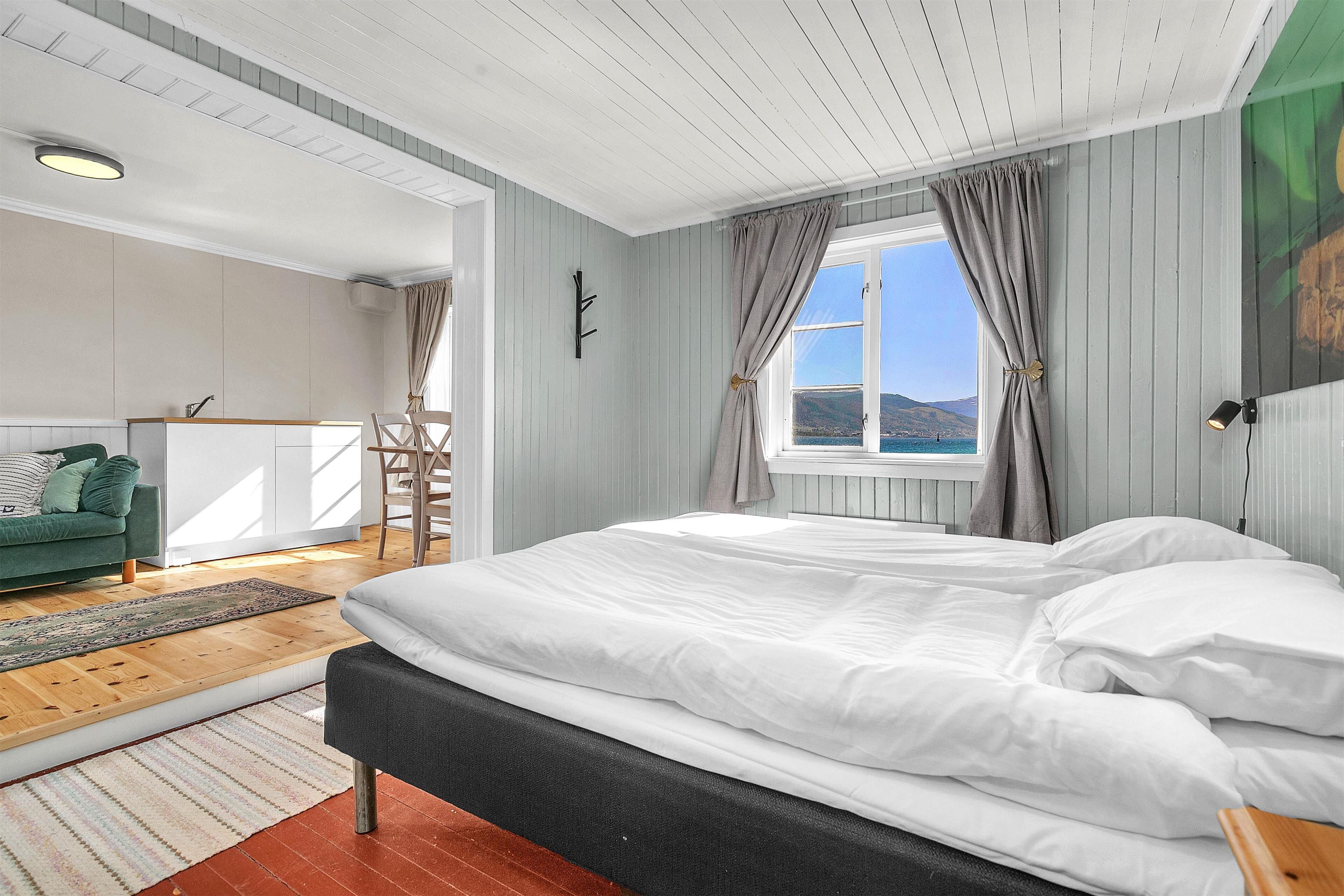 Un dormitorio con una cama grande, vistas al mar y un sofá verde en la habitación contigua.
