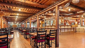 A spacious restaurant with wooden tables and chairs, a bar area, and a high wooden ceiling with exposed beams. - Sandtorgholmen Hotel, BW Signature Collection (Harstad)