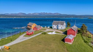 A coastal village with traditional houses, a clear blue sky, and mountains in the background. - Sandtorgholmen Hotel, BW Signature Collection (Harstad)