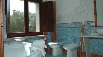 Ein Badezimmer mit einer Badewanne, zwei Toiletten, einem Waschbecken und einem Fenster.