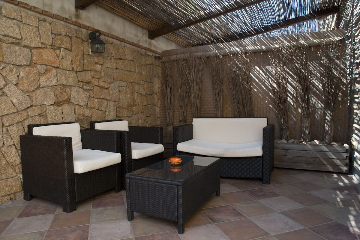 Eine Terrasse mit Korbmöbeln und einer Steinmauer.