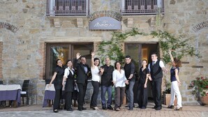 A group of people standing in front of a stone building with a sign that reads "NASCAR." - Nascar Hotel (Baunei)