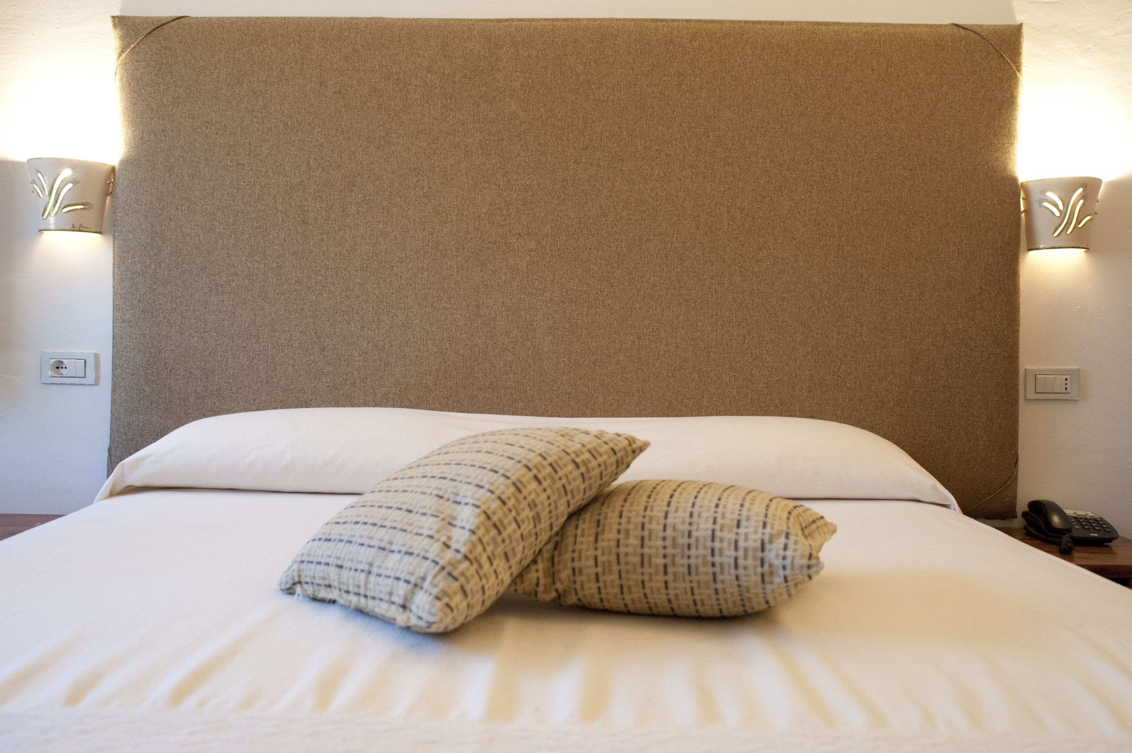 Un letto rifatto con due cuscini e una testiera.