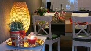 A dining area with a table set for two, featuring a candle, a tray with glassware, and a magazine. - Appartementen Valkenburg (Valkenburg aan de Geul)