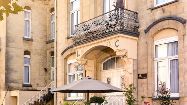 A historic building with ornate balconies, a statue, and a sign indicating room number 38. - Appartementen Valkenburg (Valkenburg aan de Geul)