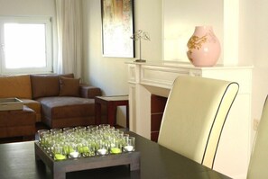 Un salon avec un canapé, une table basse sur laquelle se trouvent des verres, un vase et une cheminée.
