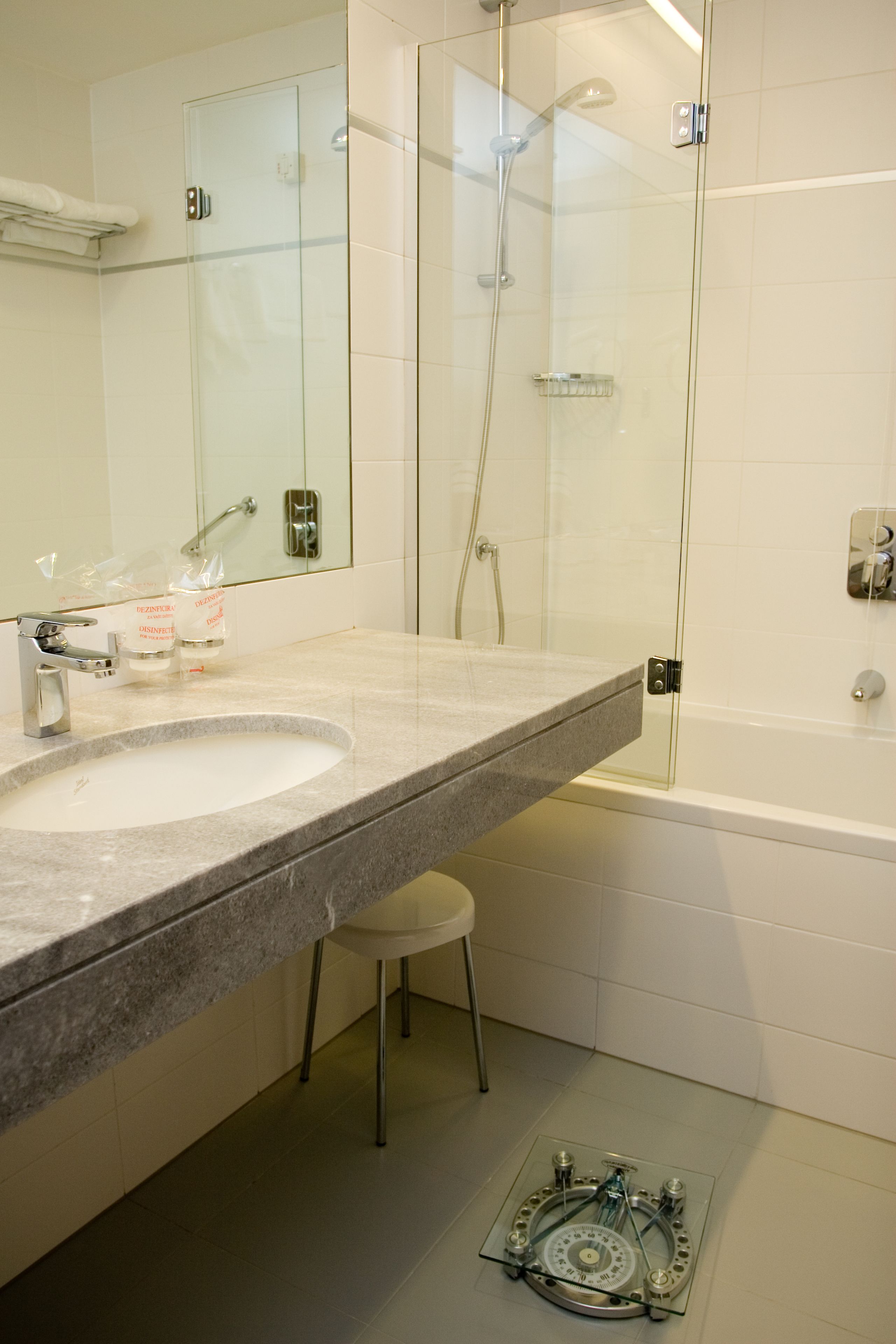 A modern bathroom with a large sink, mirror, glass shower enclosure, and a bathtub.