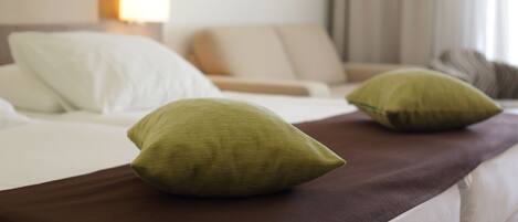 A bed with two pillows and a brown blanket.