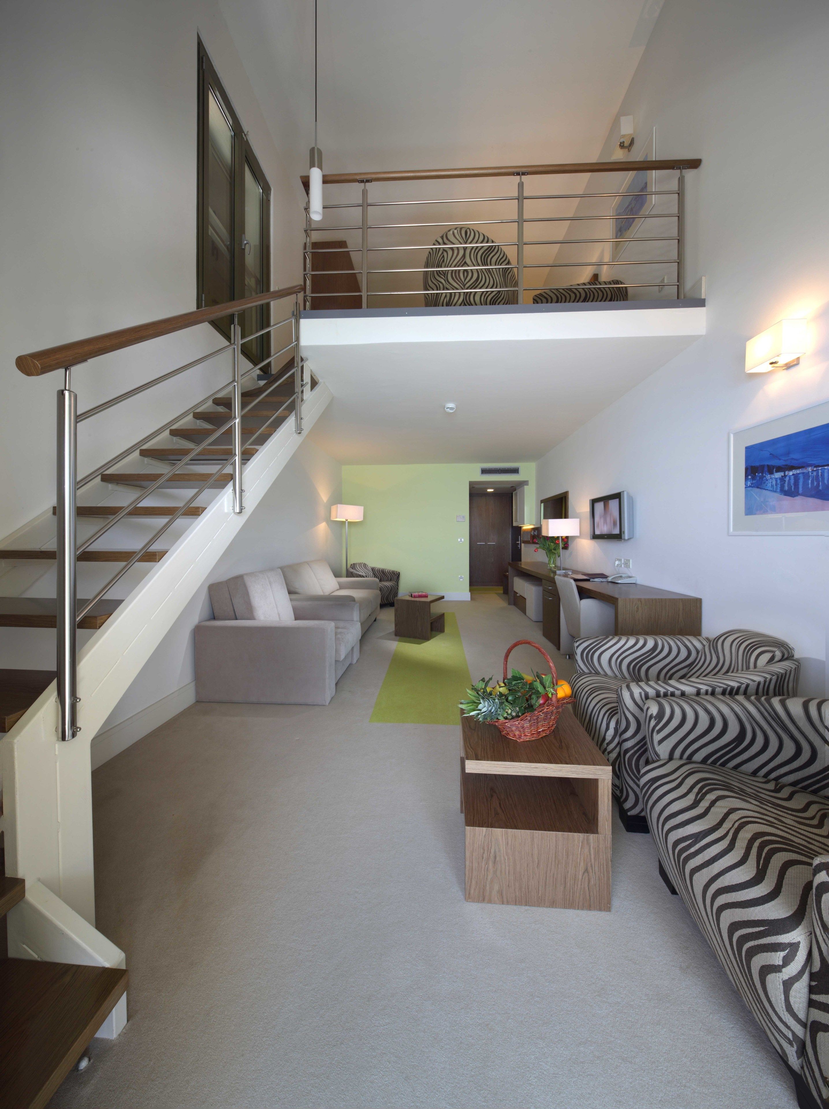 A modern living room with a staircase, a sofa set, a coffee table, and a dining area.