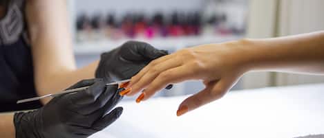 Primer plano de una sesión de manicura, con énfasis en las manos y el esmalte de uñas.
