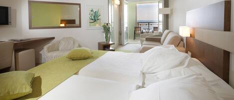 Quarto de hotel com cama, escrivaninha, cadeira e vista para a varanda.
