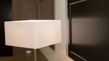 Une chambre moderne dotée d’un grand téléviseur à écran plat fixé au mur, d’un lampadaire blanc et d’une porte en bois.