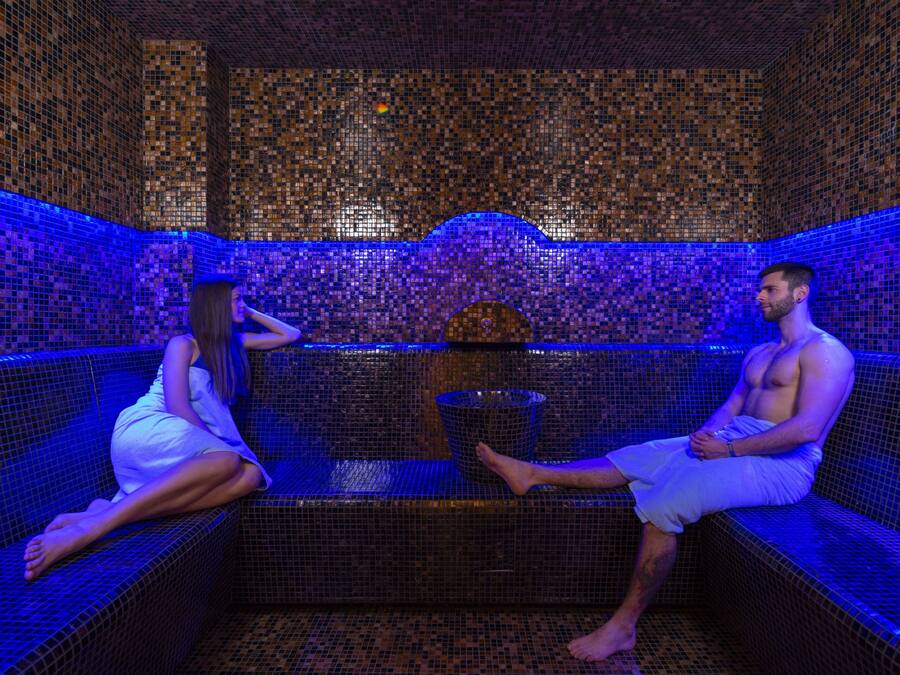 A room with mosaic tile walls and a central water feature.