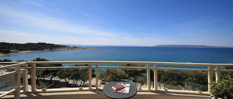 A balcony with a view of the sea, a small table with a book and magazine, and a railing.