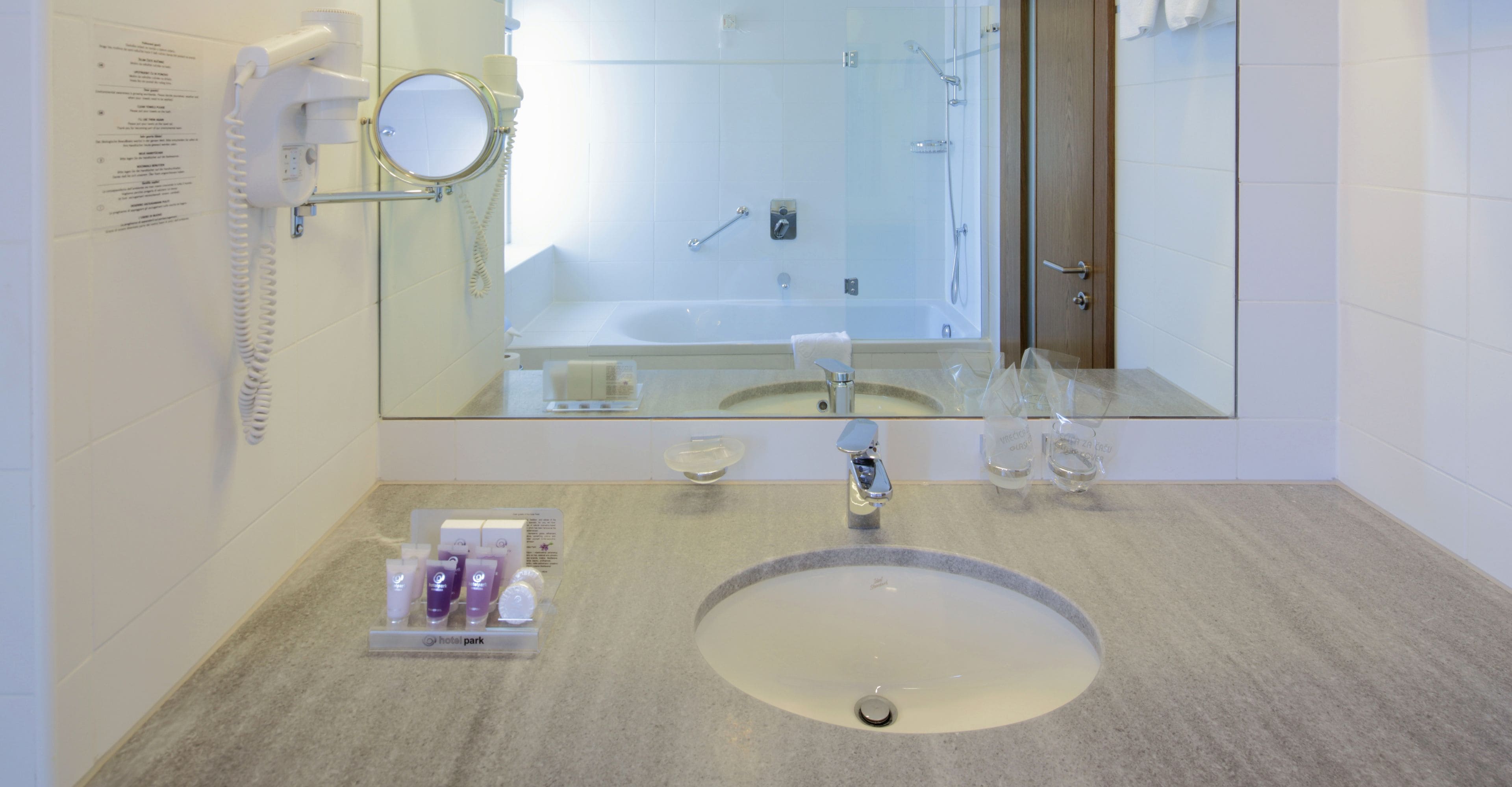 A hotel bathroom with a sink, mirror, and shower.