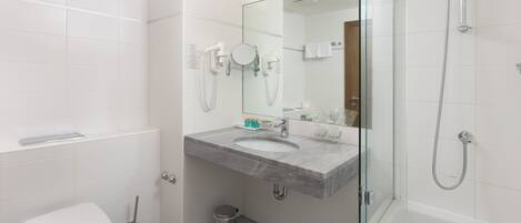 Un baño moderno con inodoro, lavamanos y ducha.