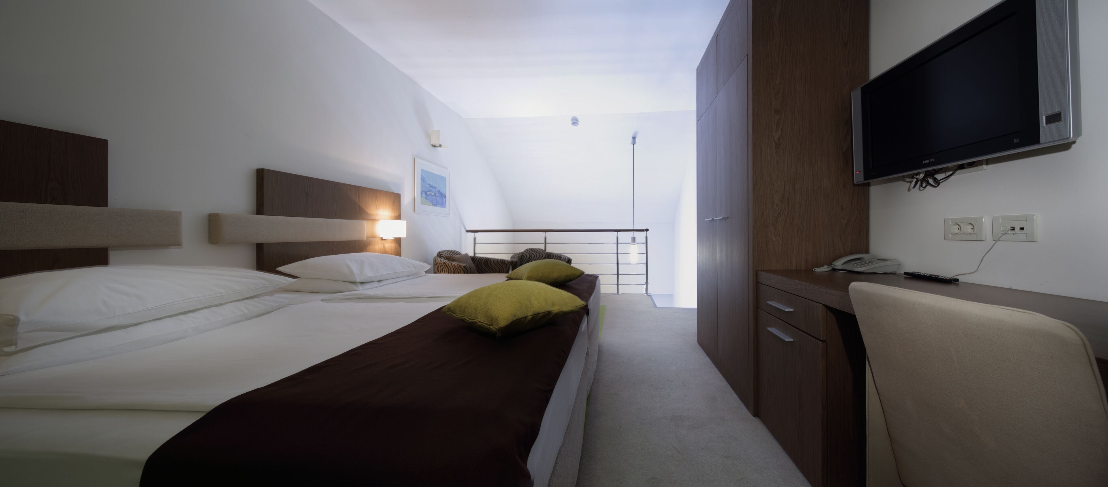 Habitación de hotel con dos camas, un escritorio, una silla, un televisor y un baño.