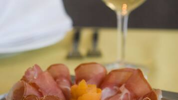 Ein Teller Prosciutto und ein Glas Weißwein auf einem Tisch.