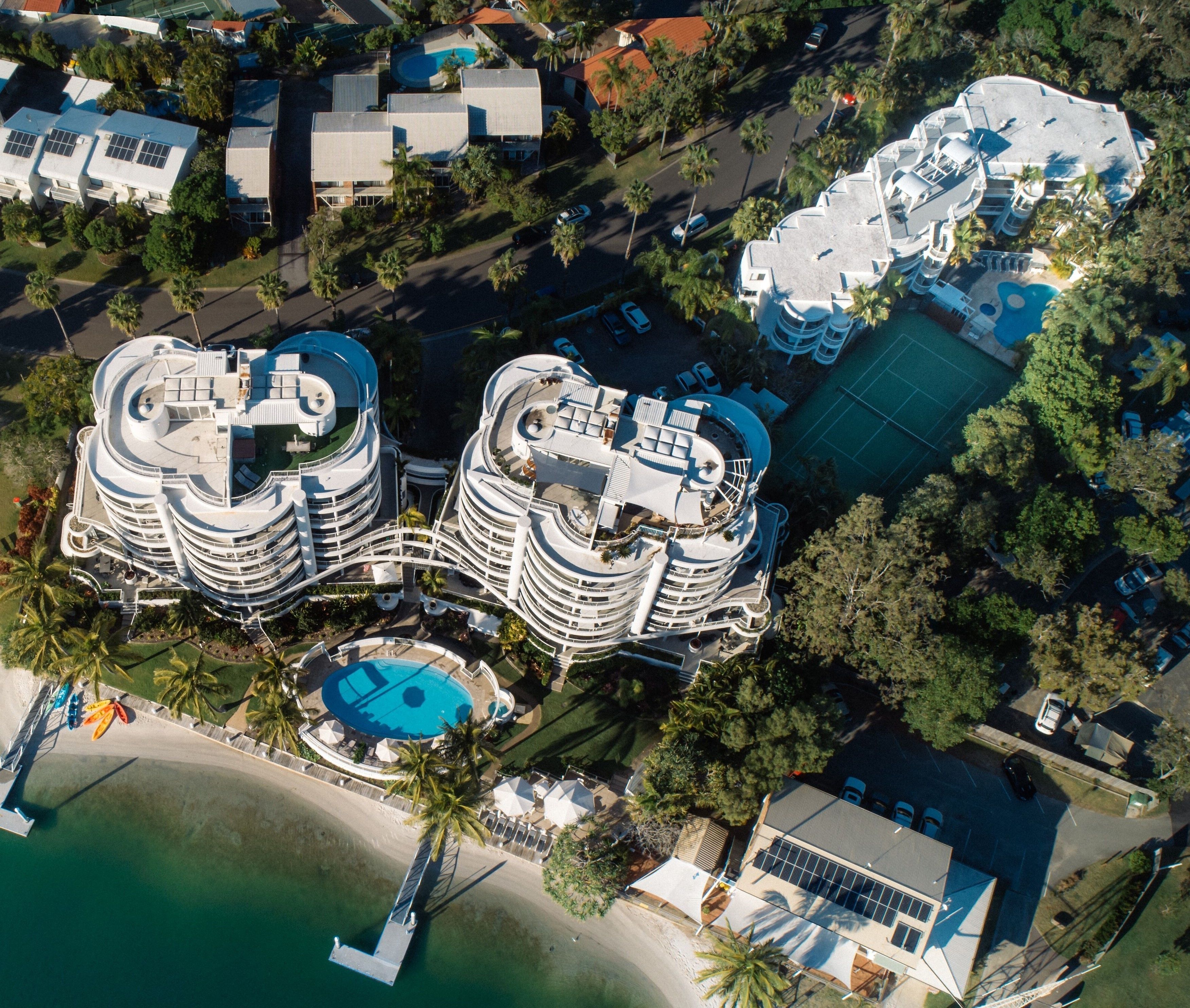 A high-rise hotel with multiple balconies, a central pool, and a beach area.
