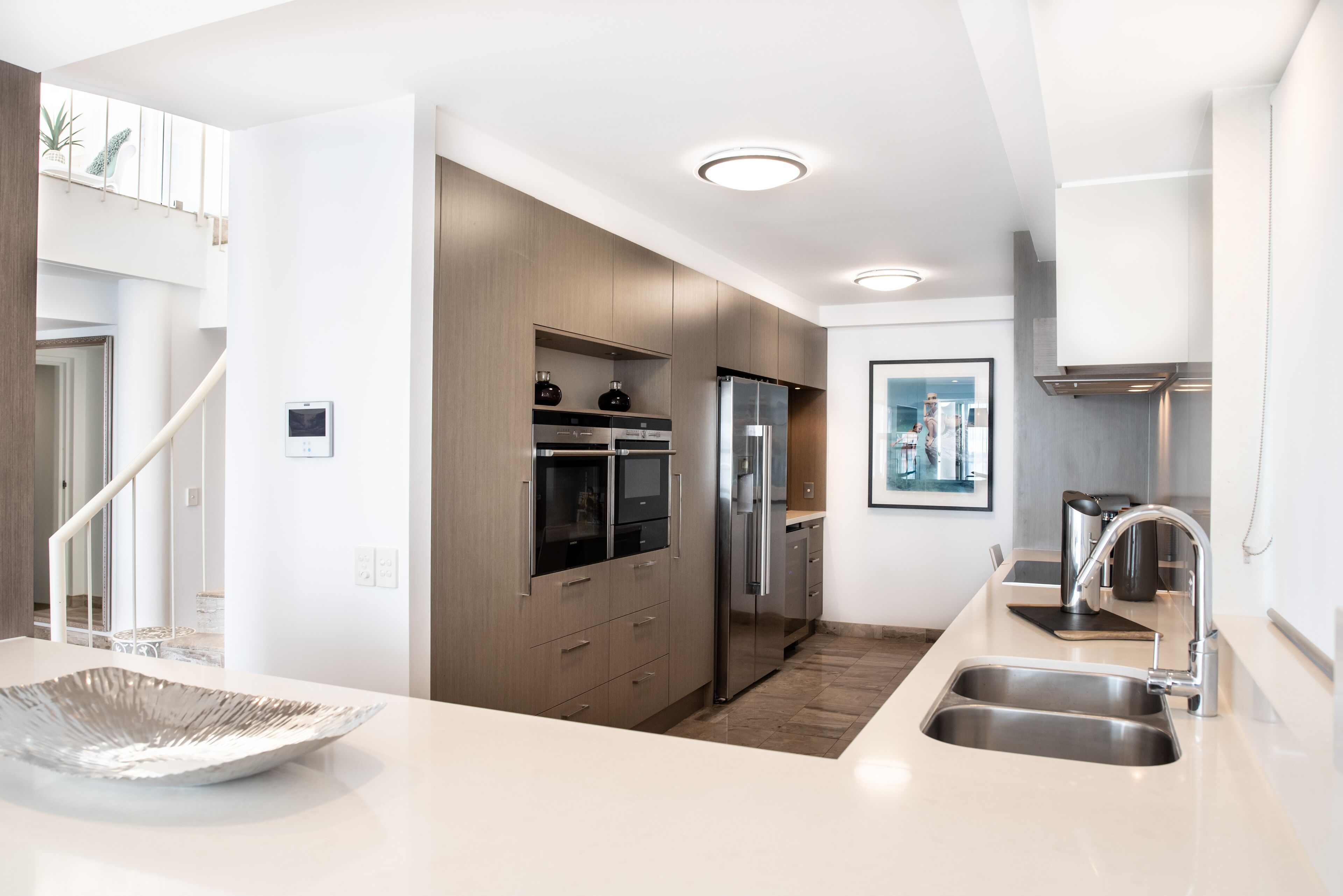 A modern kitchen with stainless steel appliances, a white countertop, and a built-in oven.
