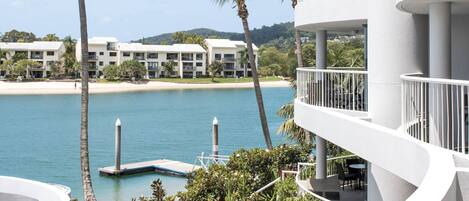 A modern hotel with a pool, palm trees, and a view of the beach.