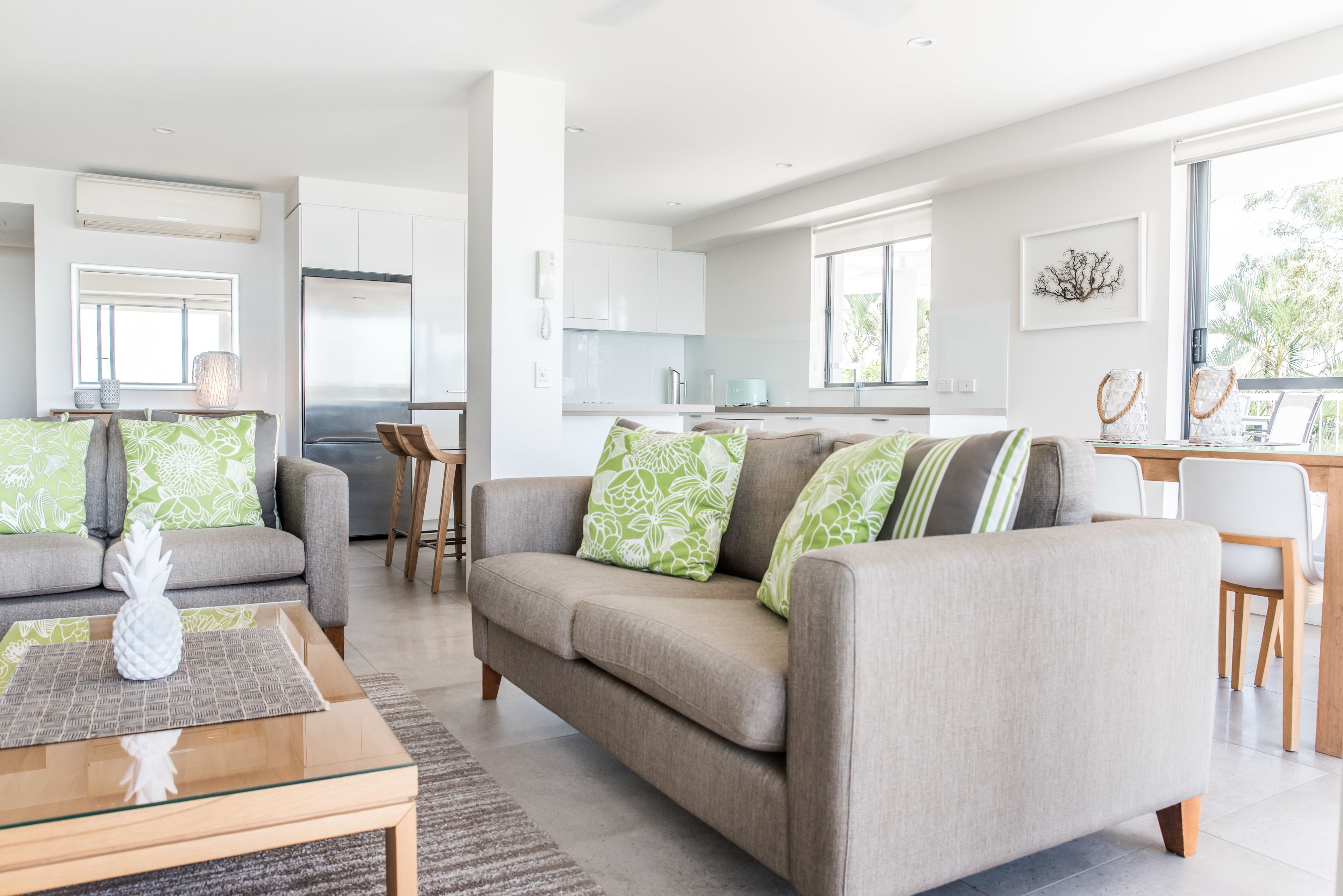 A modern living room with a sofa, coffee table, and a view into the kitchen.