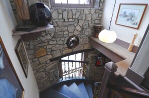 A stone wall with a mirror, a staircase with a wooden railing, and a framed picture on the wall. - Orchard Hotel (Falkirk)