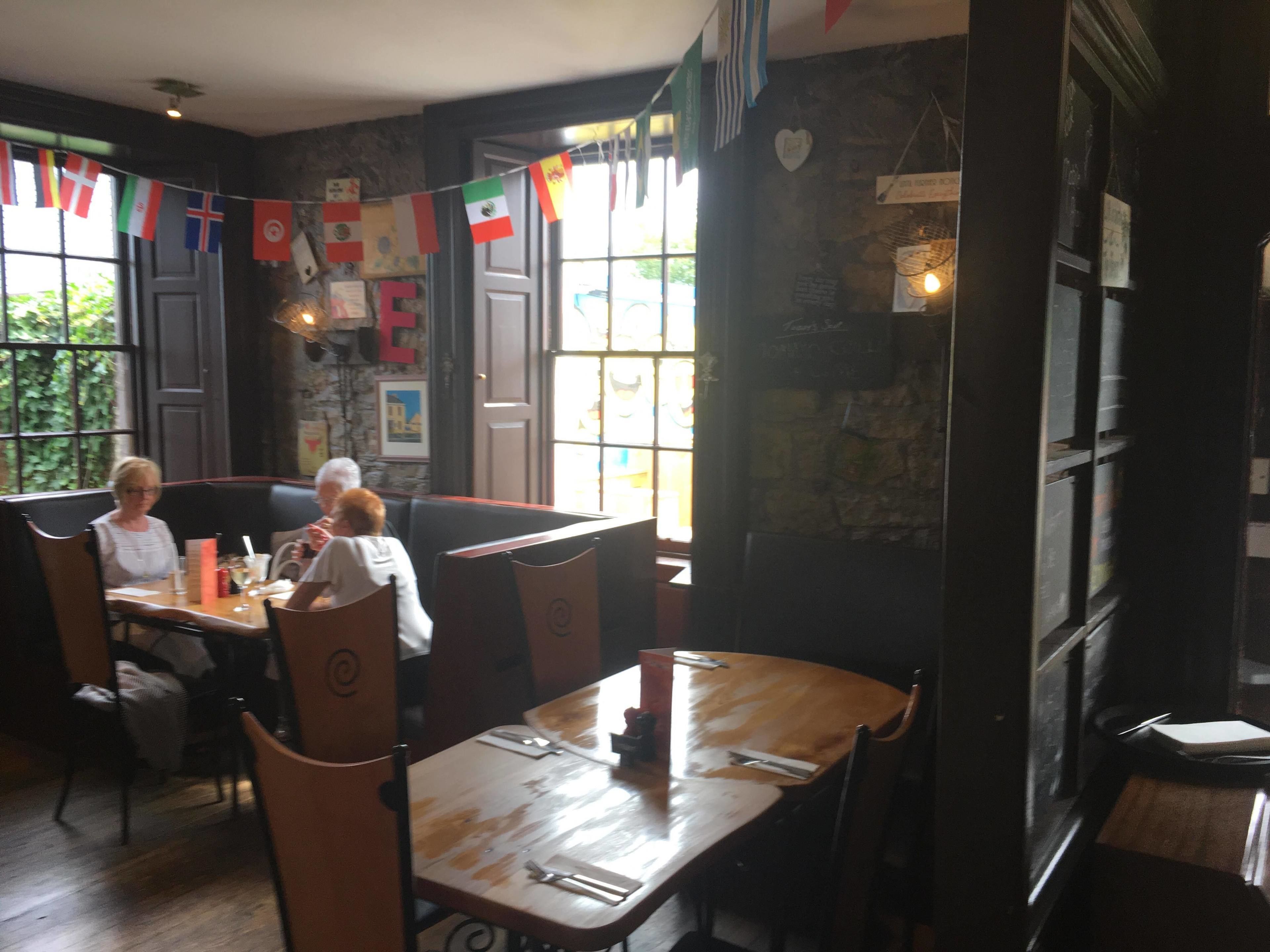 A restaurant interior with booths, a stone wall, and flags on the windows.