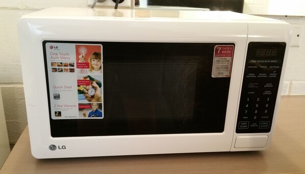 Un four à micro-ondes LG blanc, doté d’un écran numérique, d’un panneau tactile et d’un autocollant indiquant une garantie de deux ans.