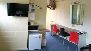 A small, compact room with a television, microwave, refrigerator, and a mirror. - A & A Lodge Motel Emerald (Emerald)