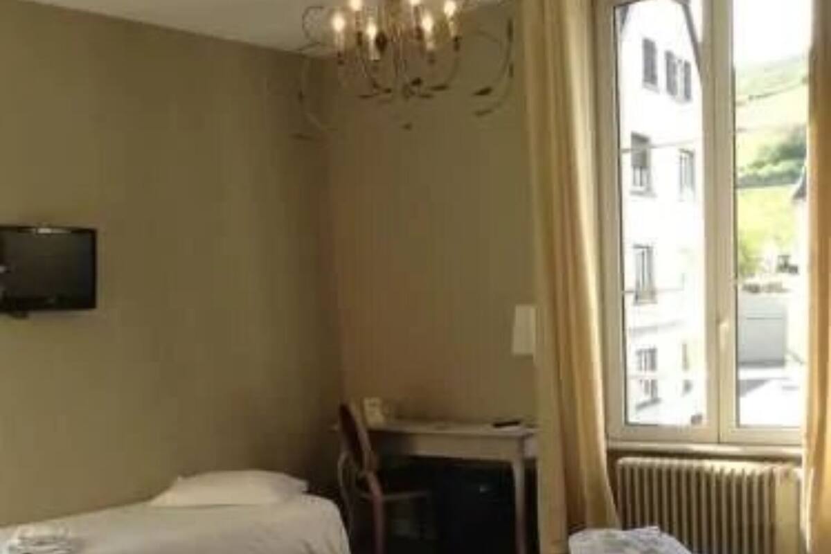 A hotel room with two single beds, a desk, a chair, and a TV.