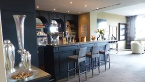 A bar area with a counter, bar stools, and a variety of bottles and glasses. - LE H - Hôtel & Restaurant (Barr)