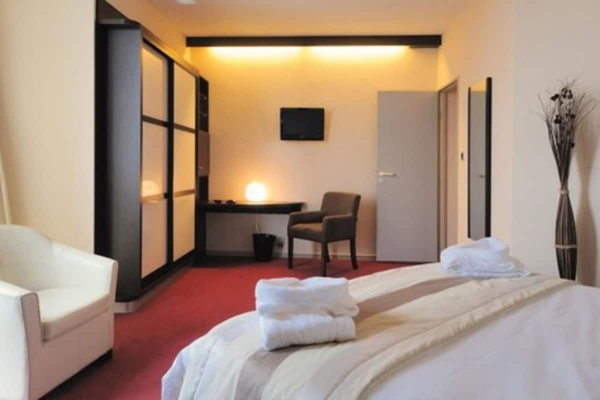 A hotel room with a bed, a desk, a chair, and a TV.