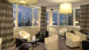 A hotel lobby with leather chairs, a glass coffee table, and large windows with curtains. - LE H - Hôtel & Restaurant (Barr)