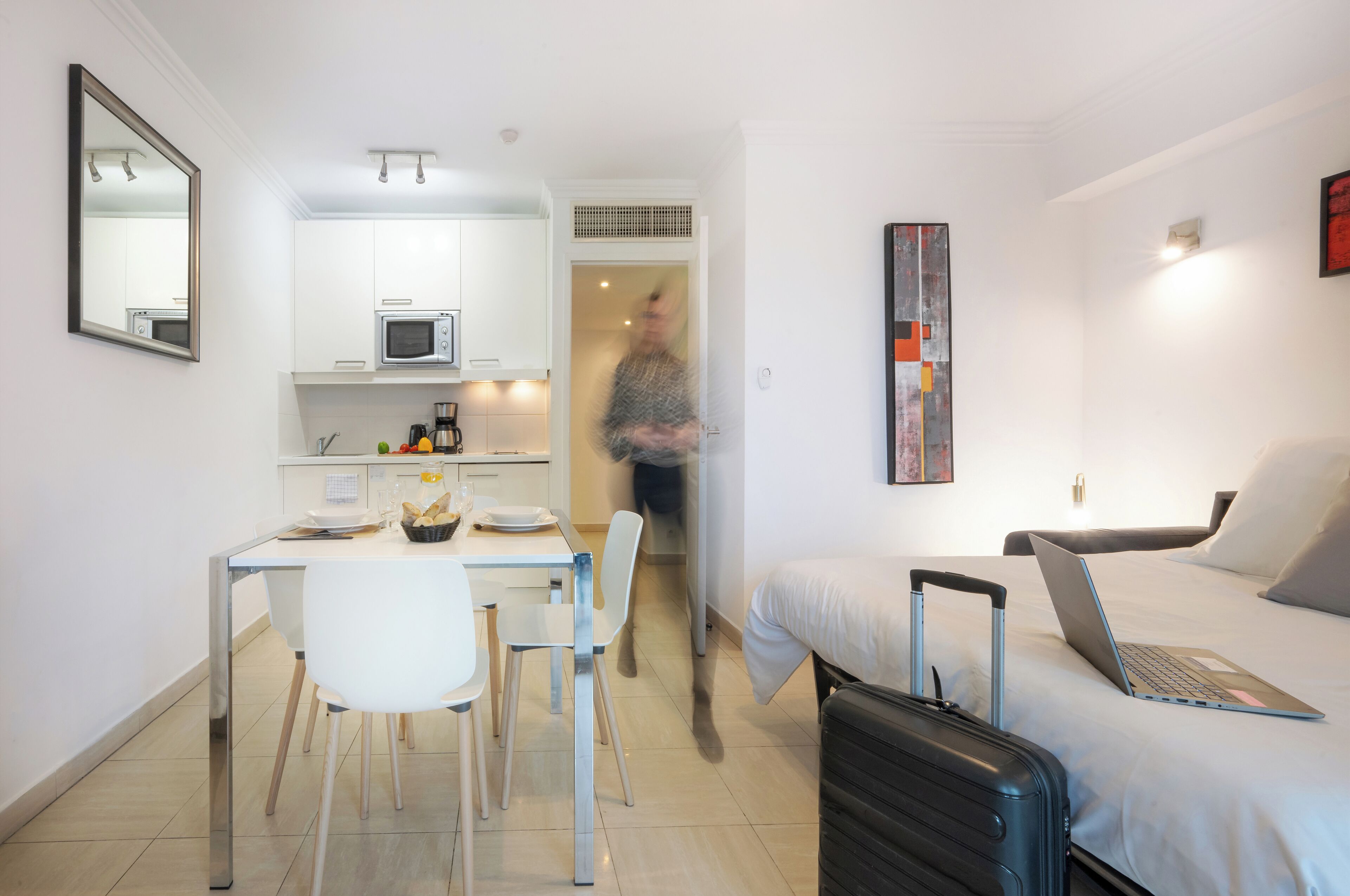 A compact hotel room with a bed, a desk, and a kitchenette.