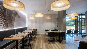 A modern dining area with wooden tables, black chairs, and large woven pendant lights. - Nemea Appart Hotel Le Lido Cagnes sur Mer (Cagnes-sur-Mer)