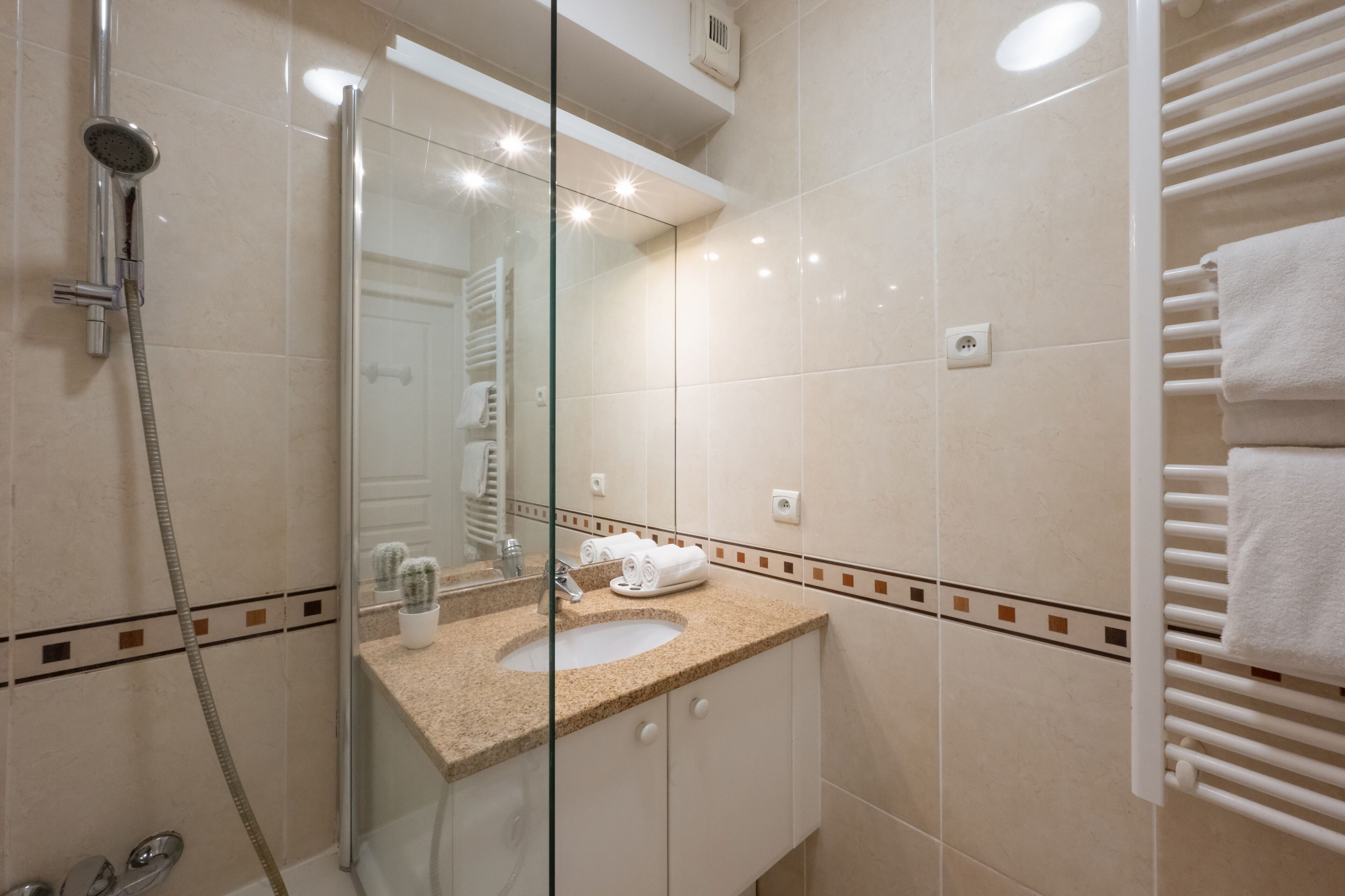 Ein modernes Badezimmer mit einer Duschkabine, einem Waschbecken mit Handtuch und einem Handtuchhalter.