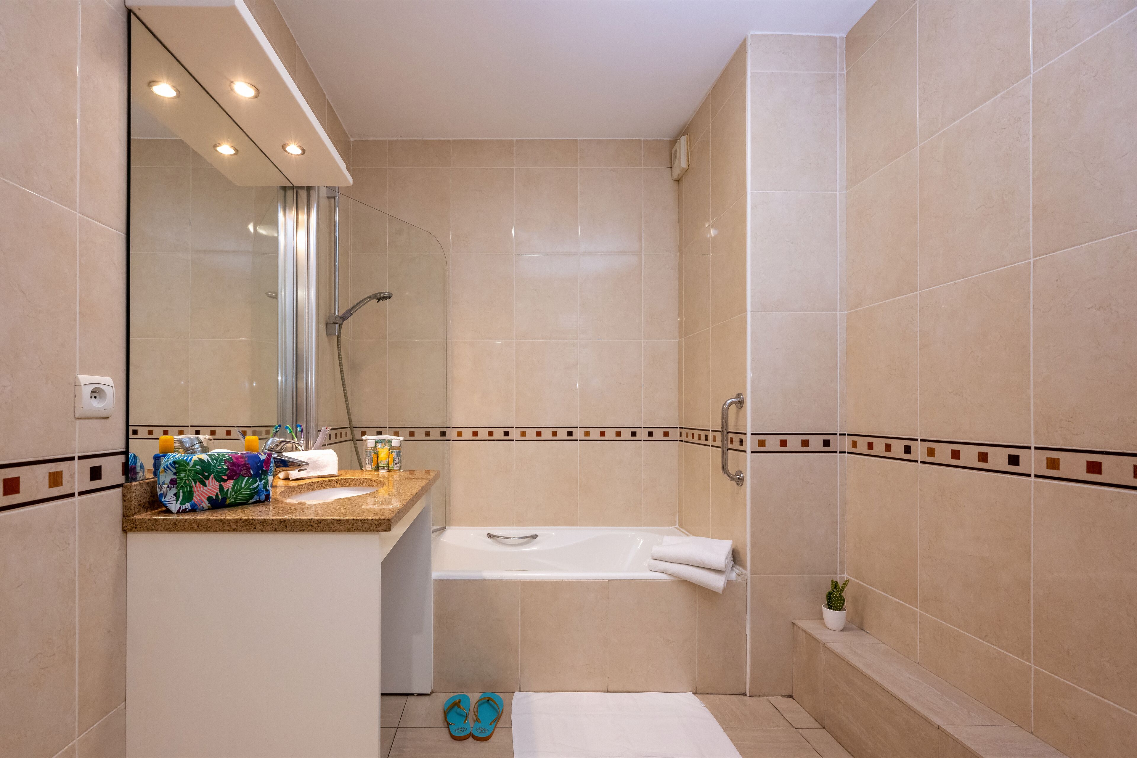 A bathroom with a bathtub, a shower, and a vanity with a mirror.