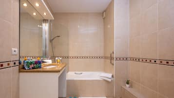 A bathroom with a bathtub, a shower, and a vanity with a mirror.