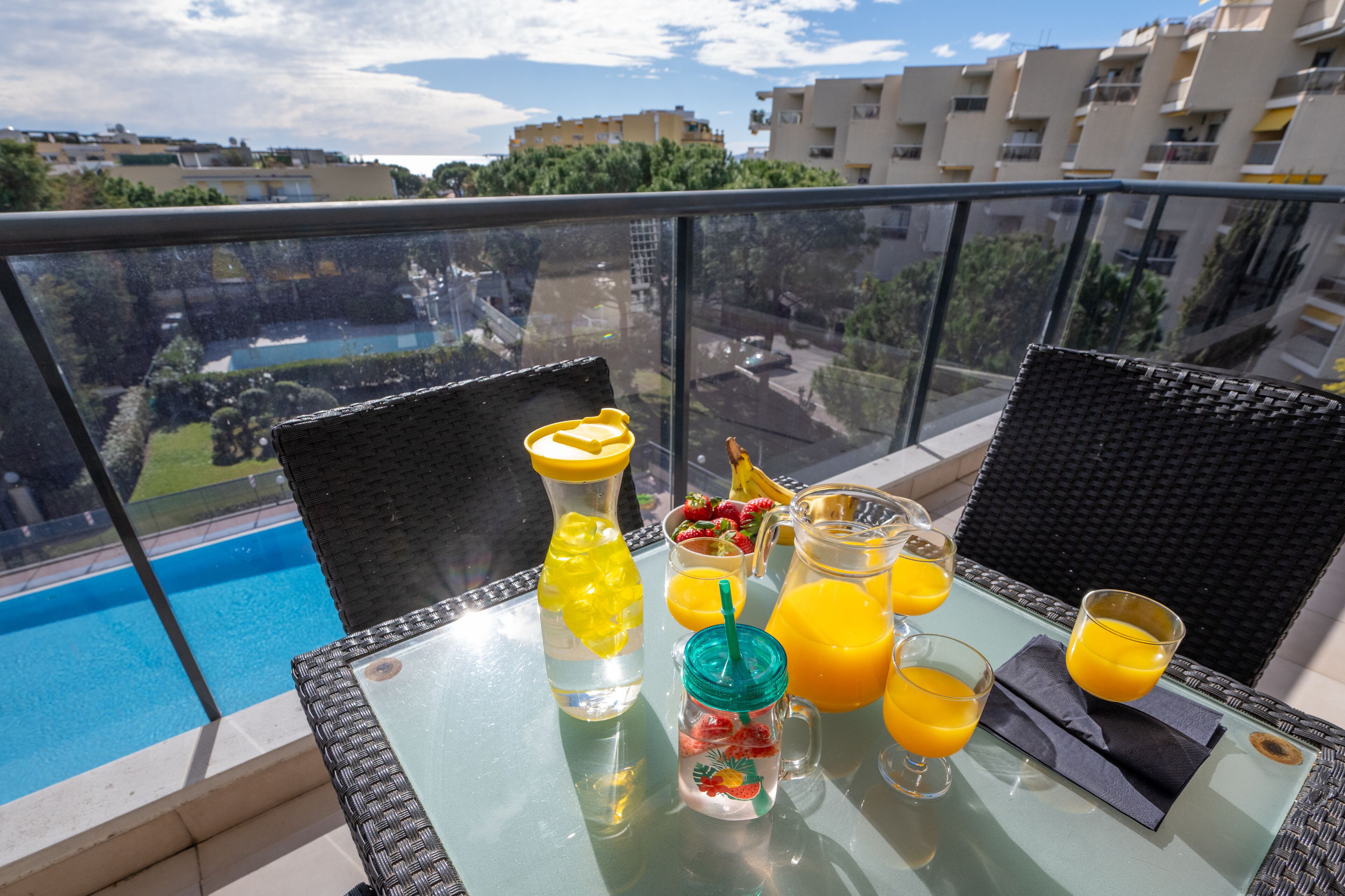 A balcony with a table set with drinks, a bottle, and a fruit pitcher.