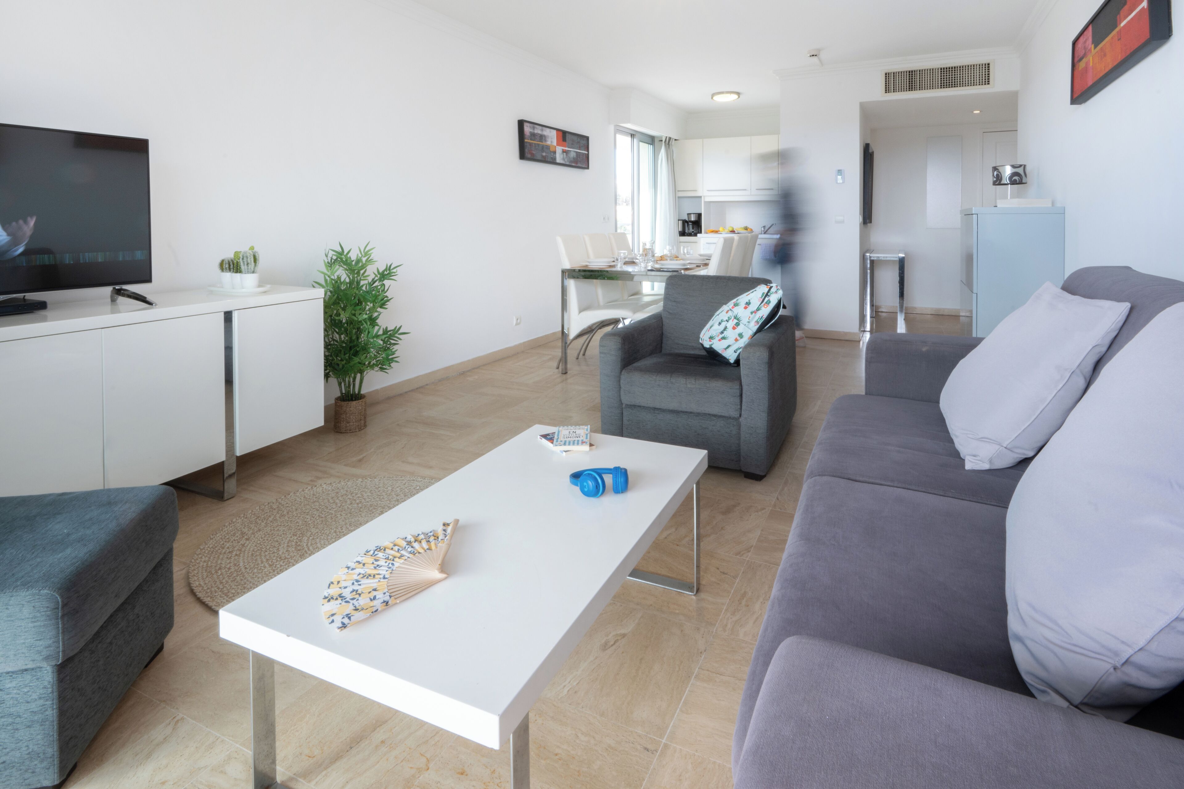 A modern living room with a grey sofa, a white coffee table, and a flat-screen TV.