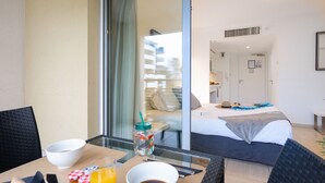 A hotel room with a bed, a dining table with breakfast items, and a view of the hotel interior. - Nemea Appart Hotel Le Lido Cagnes sur Mer (Cagnes-sur-Mer)