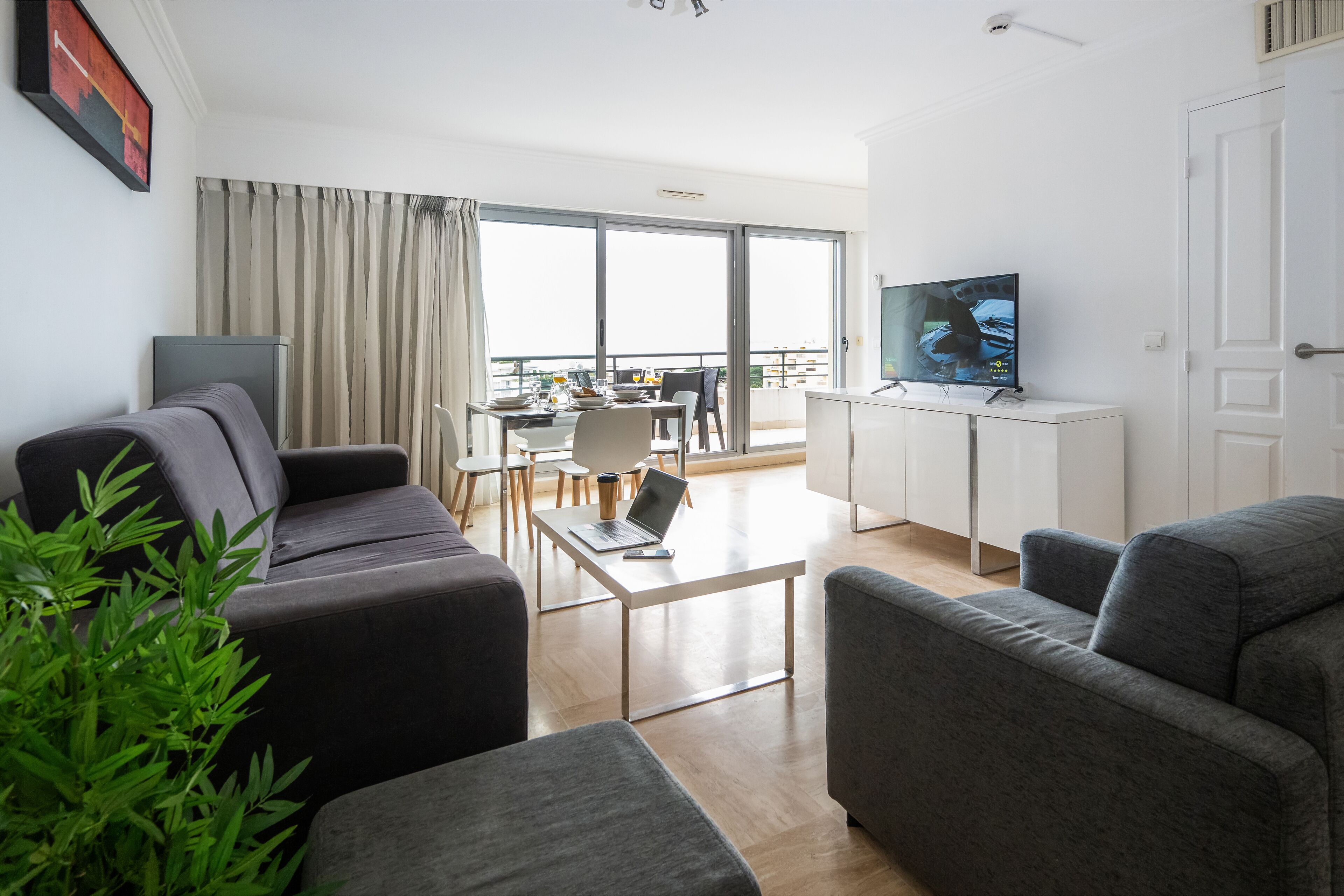 Una sala moderna con un sofá, una mesa de centro y un televisor sobre un mueble.