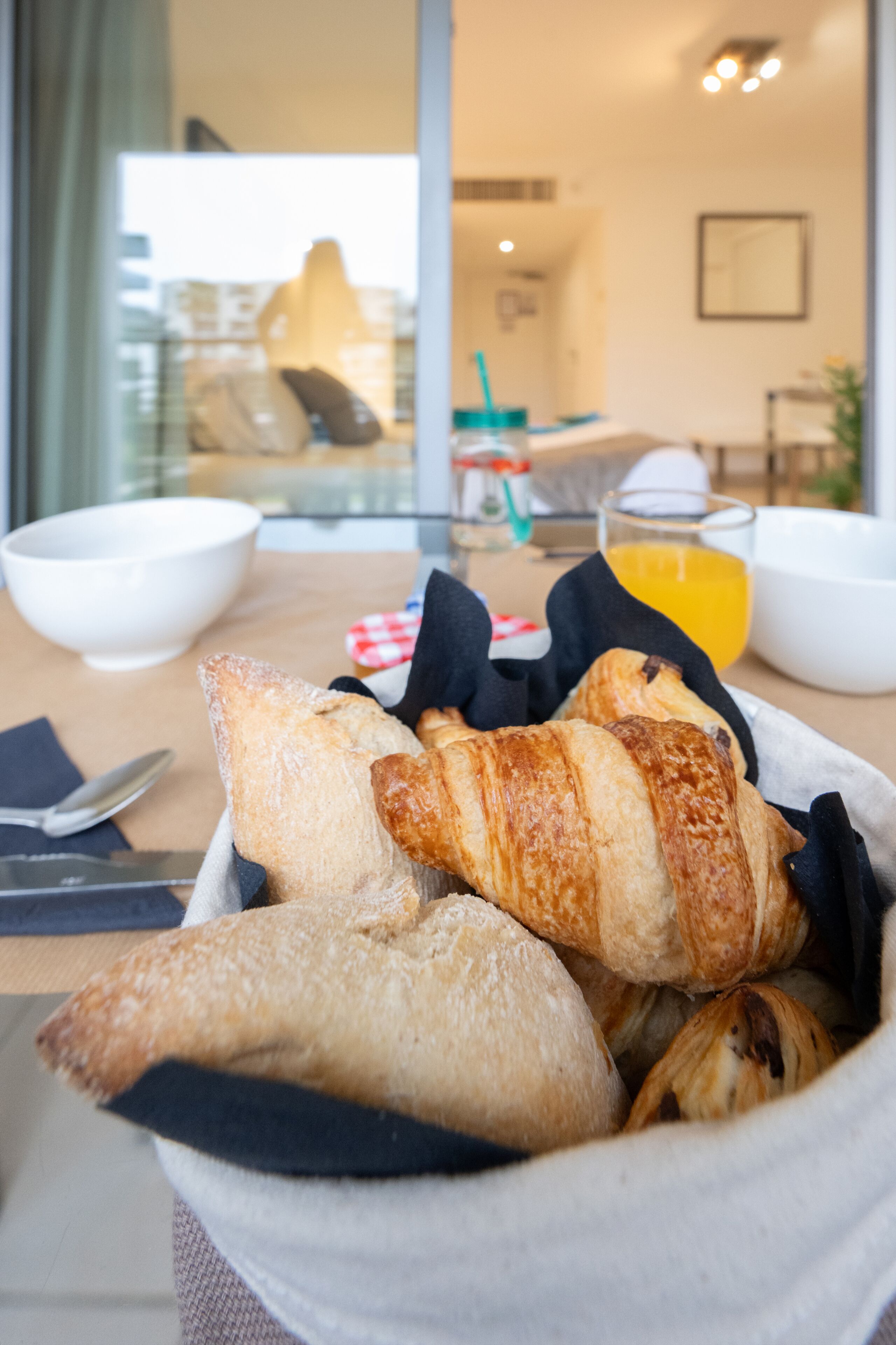 A breakfast setting with croissants and a glass of orange juice on a table.