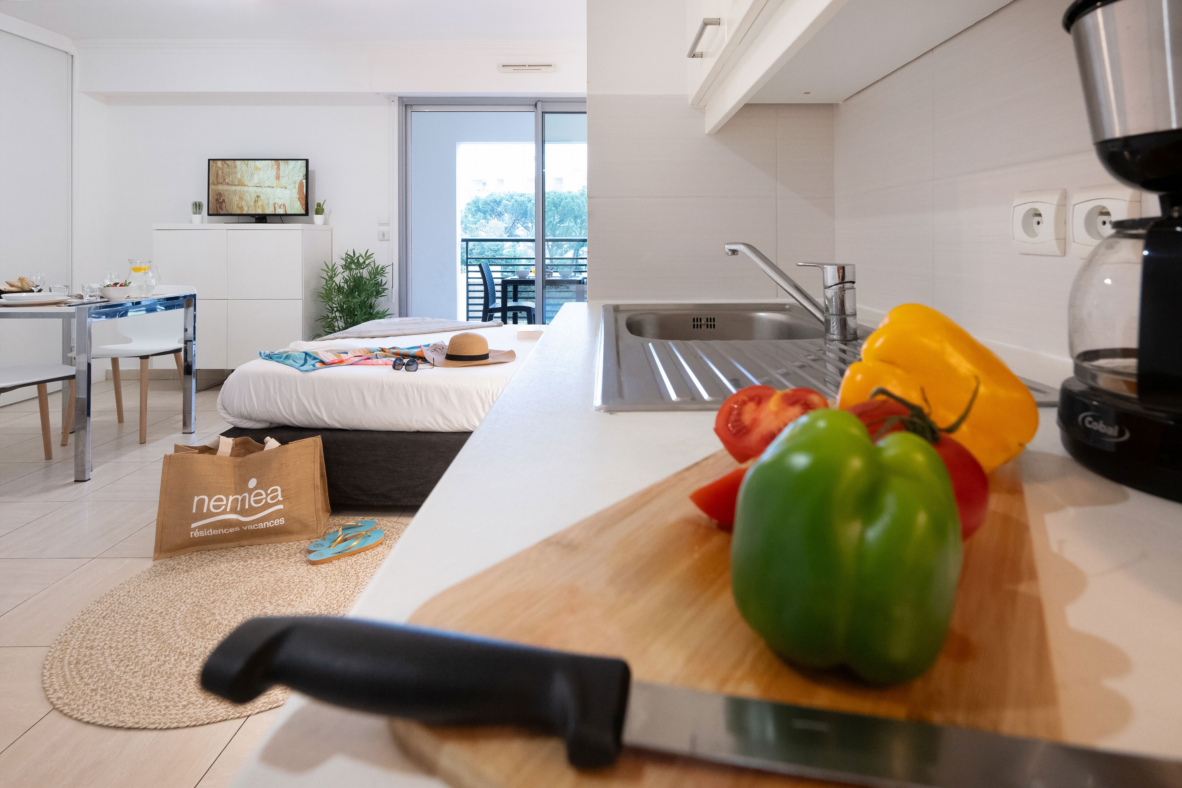 A modern kitchen with a cutting board, knife, and vegetables.